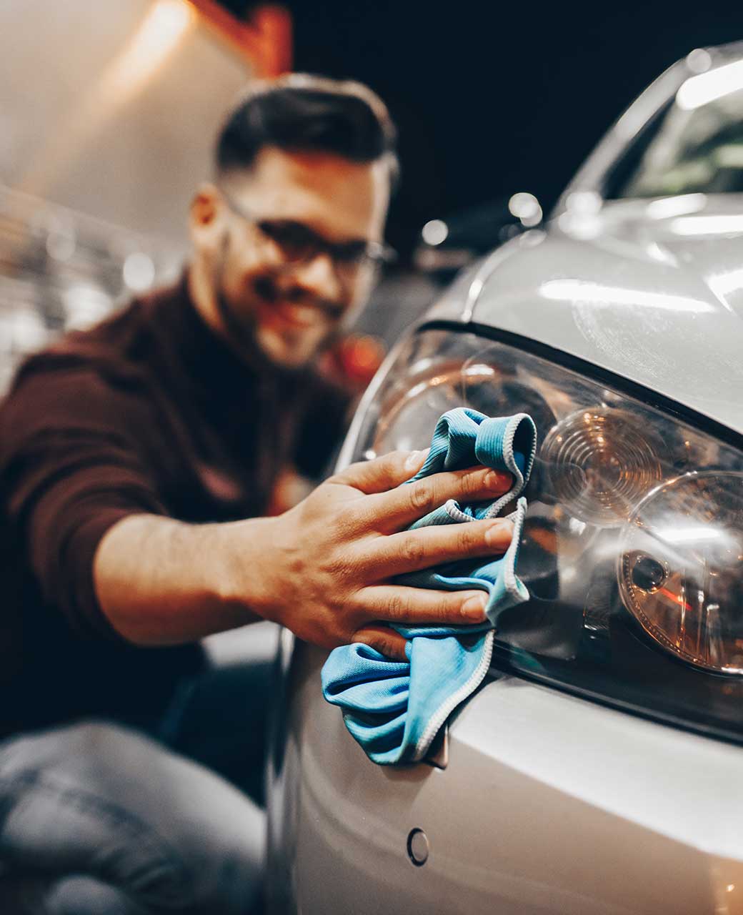 hombre limpiando los faros de su auto