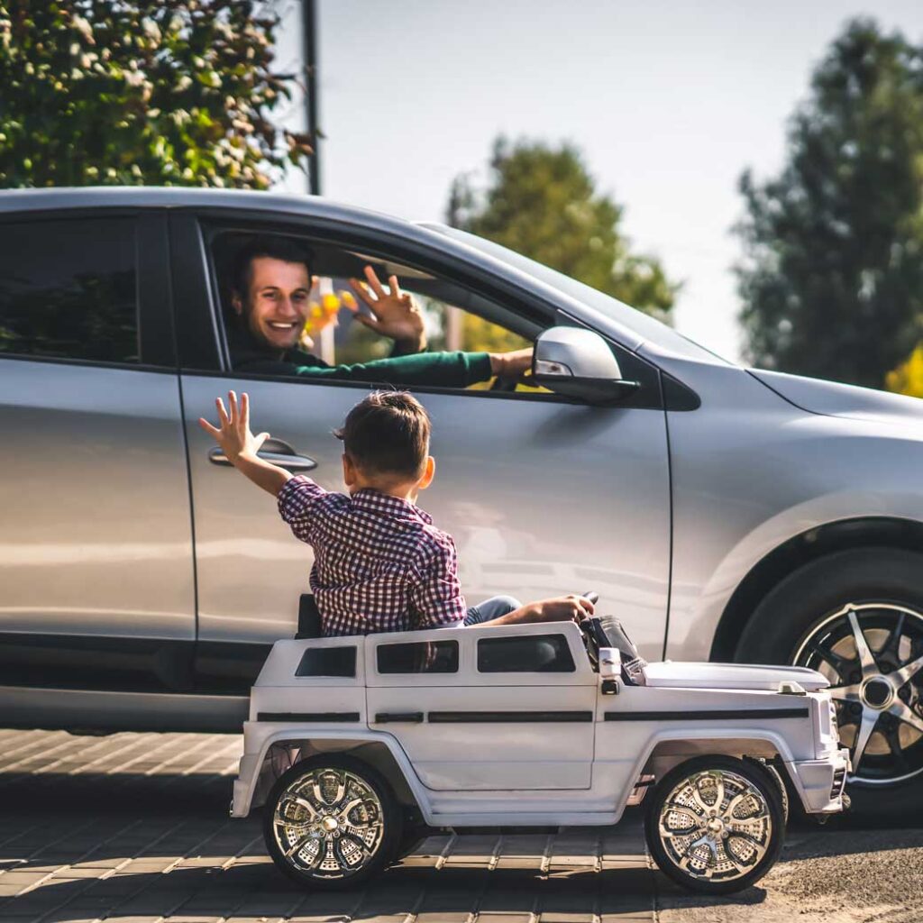 niño jugando con un auto saluda a su padre