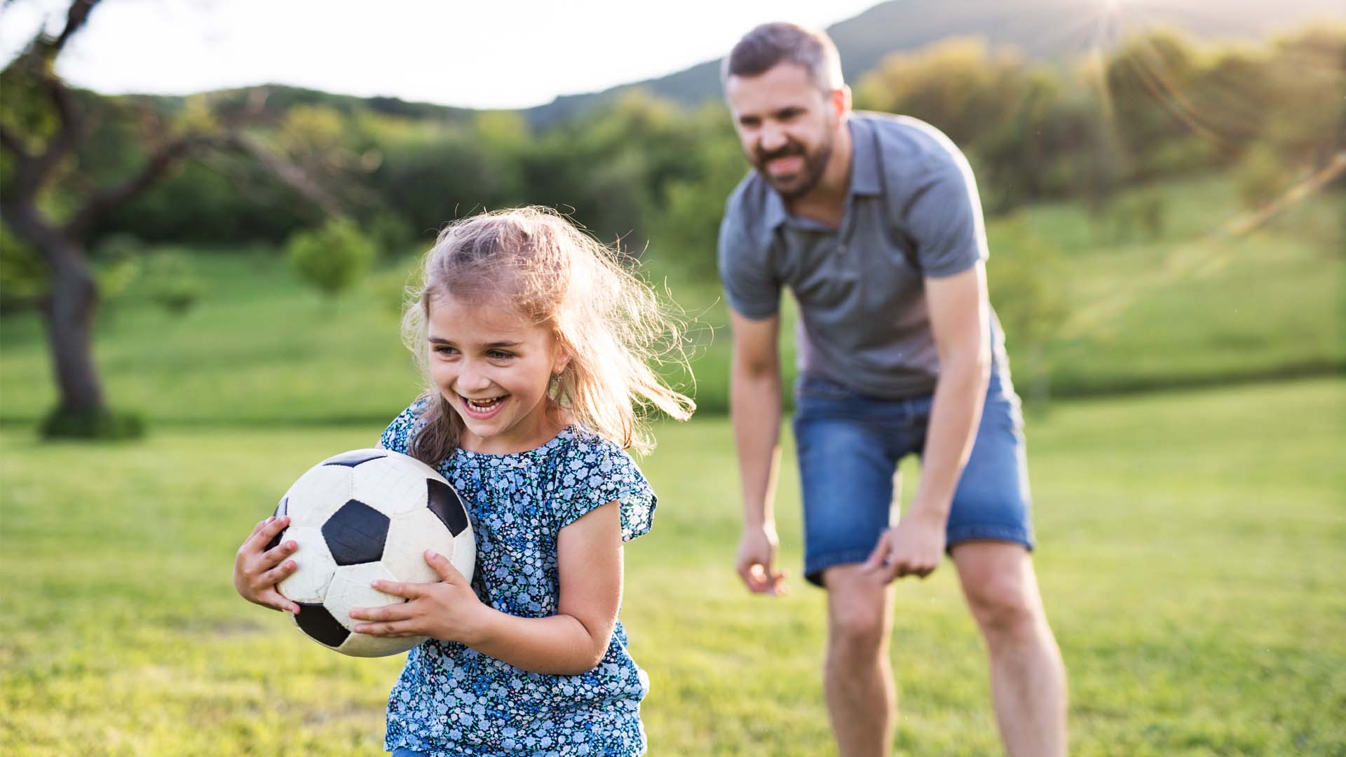 Padre de familia jugando fútbol con su hija menor