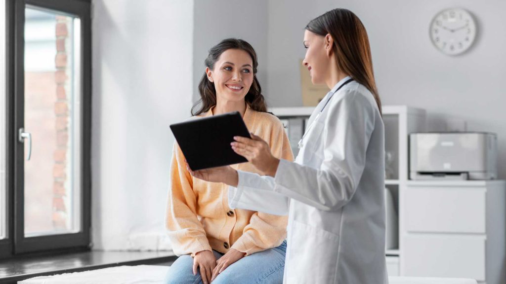 Doctora mostrándole una tablet a una paciente joven