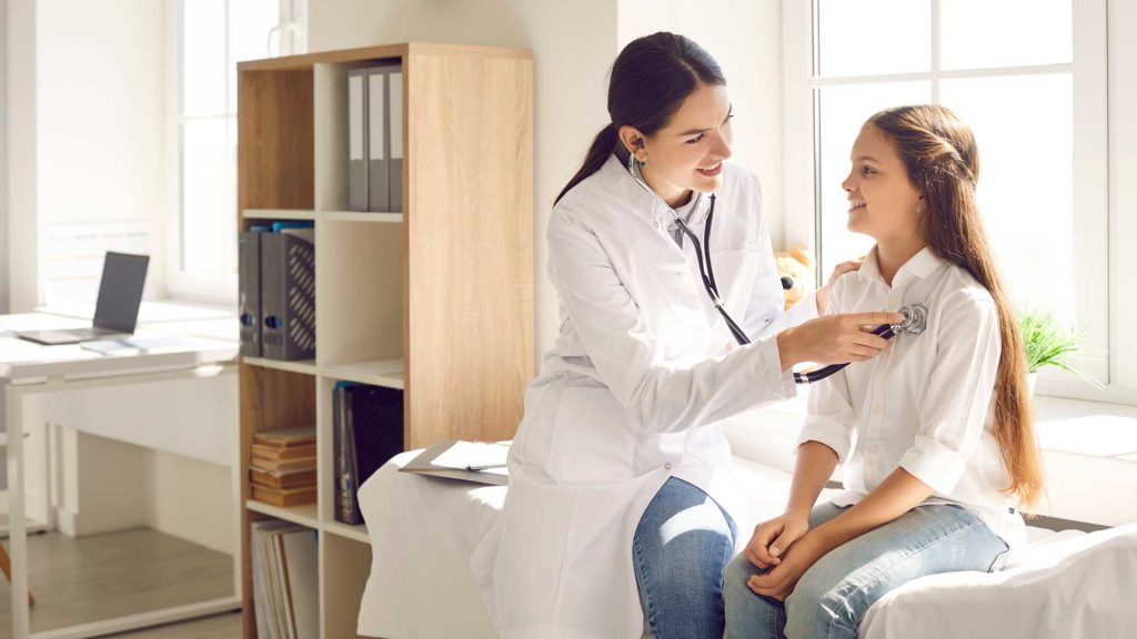 Doctora auscultando a una niña en su consultorio