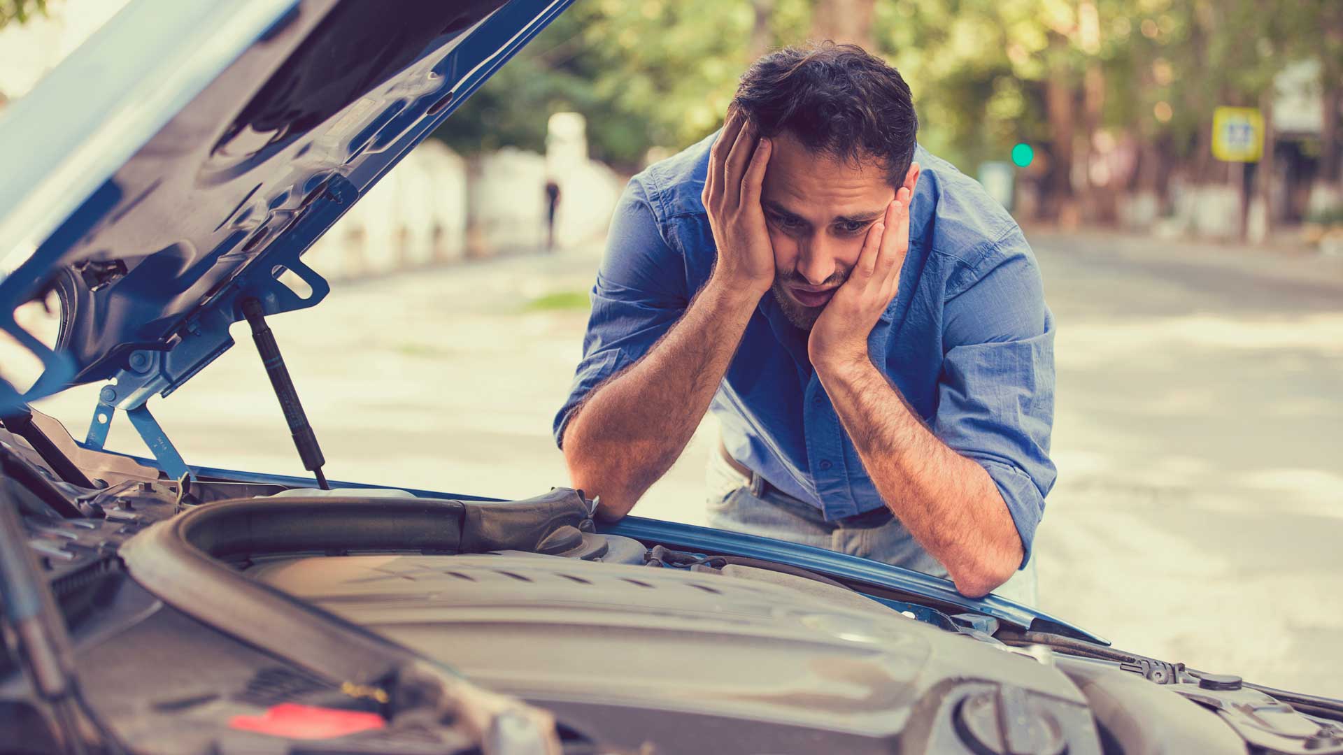 Hombre mirando al motor de su auto con expresión preocupada Hombre mirando al motor de su auto con expresión preocupada - HDI SEGUROS