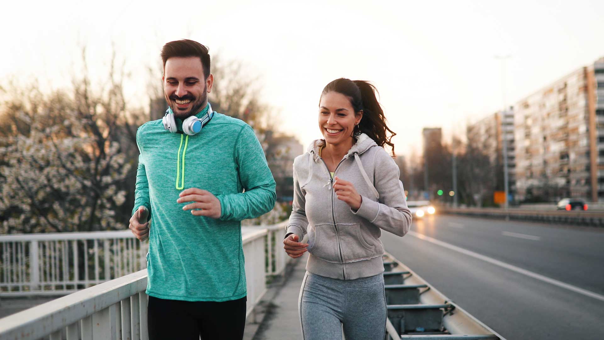 Pareja corriendo sobre la acera de una ciudad.
