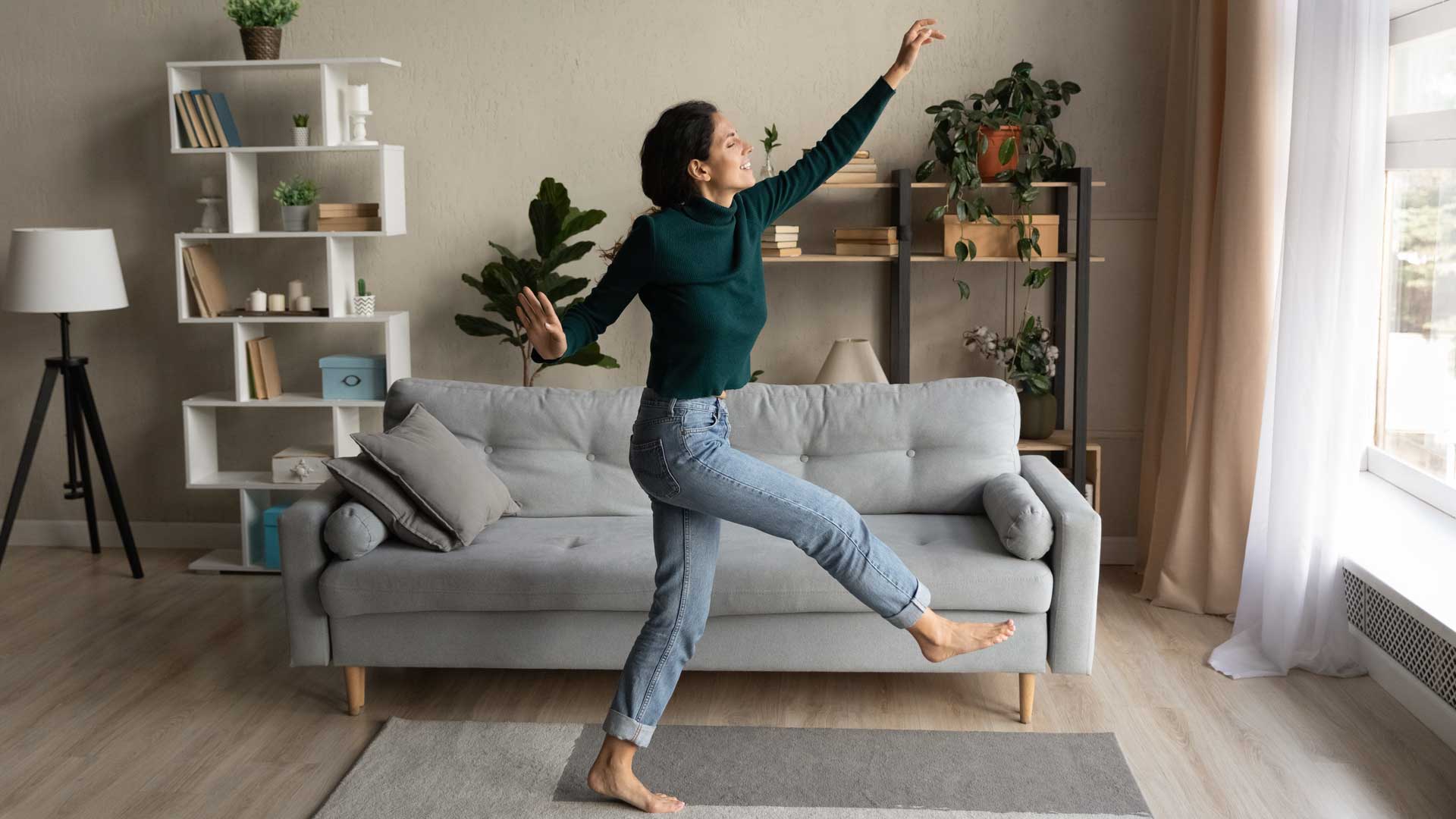 Mujer bailando en la sala de su casa.