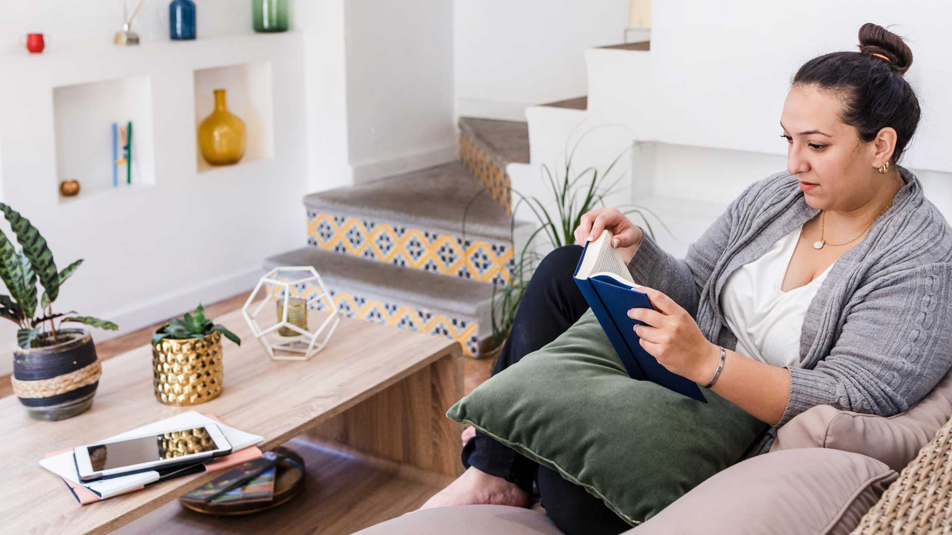 Mujer leyendo un libro en la sala de su casa.
