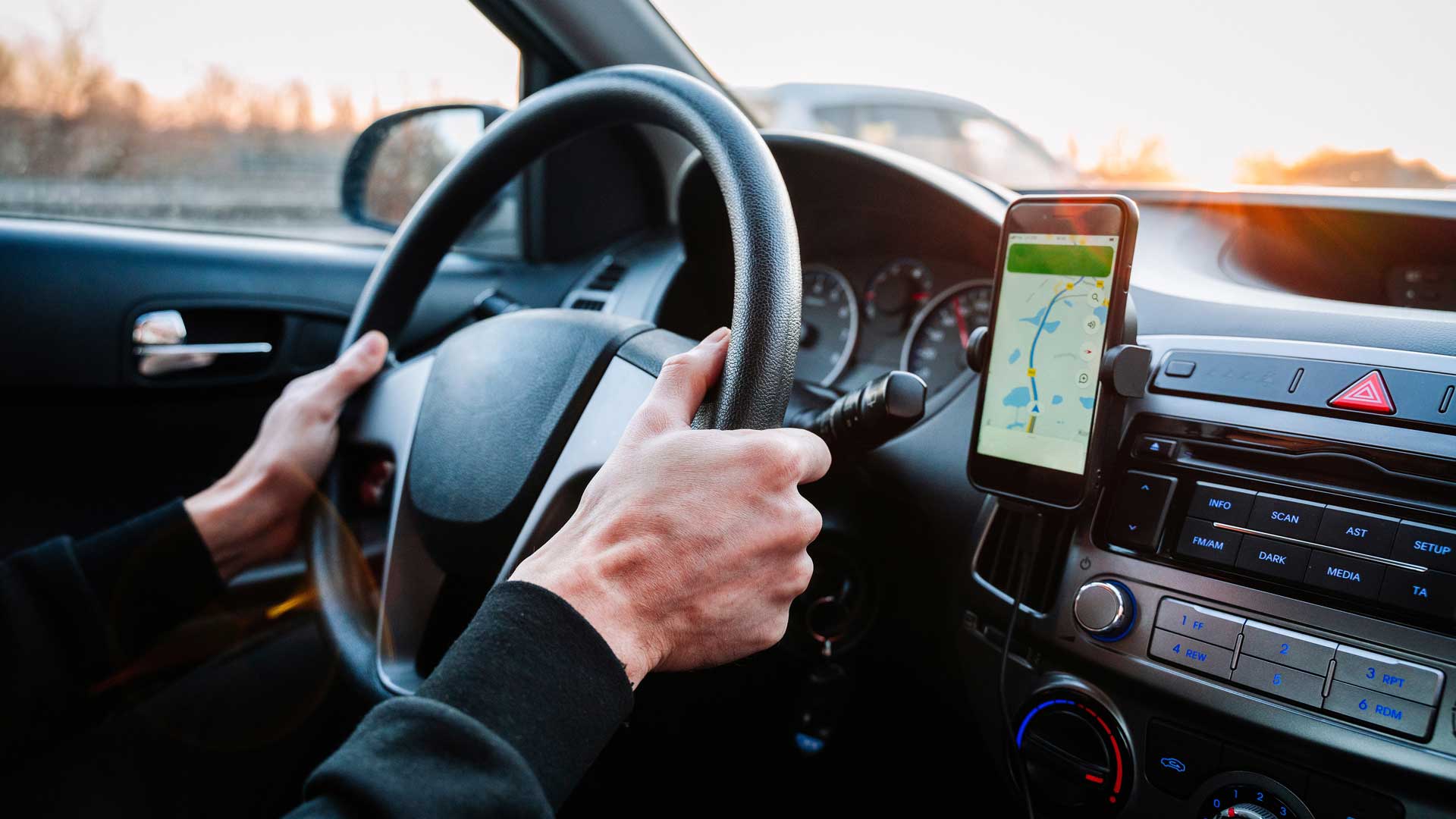 Interior de un auto con un smartphone mostrando una aplicación de mapas.