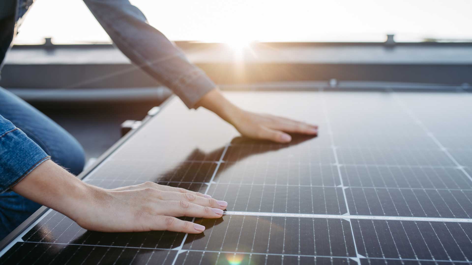 Manos de mujer sobre un panel solar.