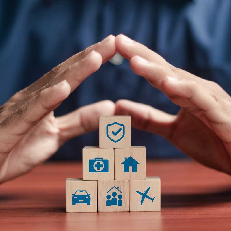 Manos envolviendo bloques con símbolos de seguros
