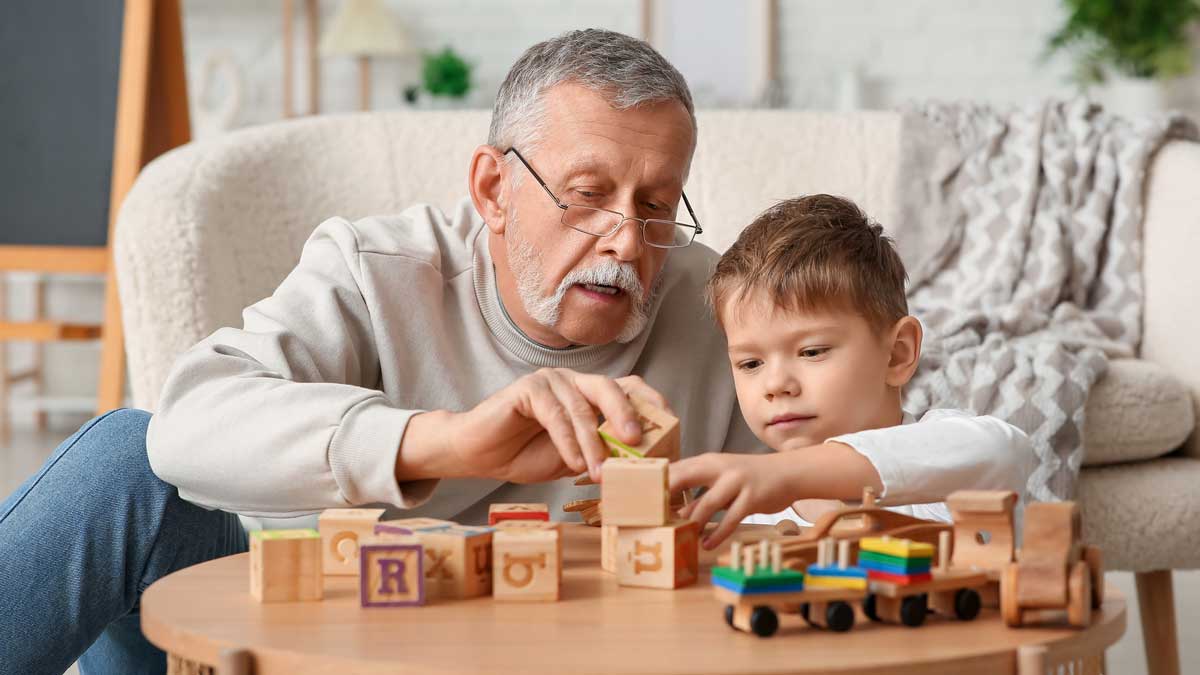 Abuelo jugando con su nieto en la sala de su casa con ambiente seguro.