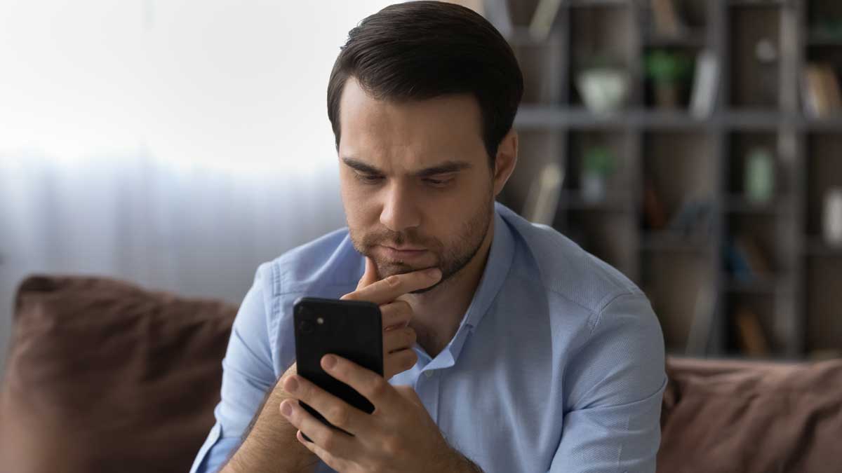 Hombre revisando su póliza de seguro de auto desde su celular en casa.