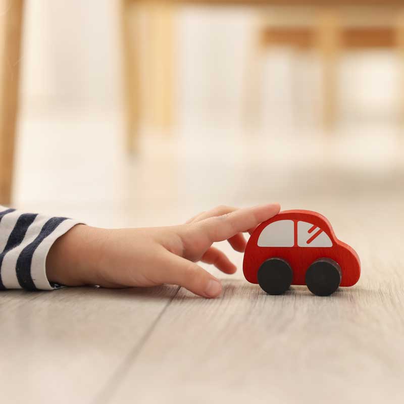 Mano de infancia protegiendo un auto de juguete.