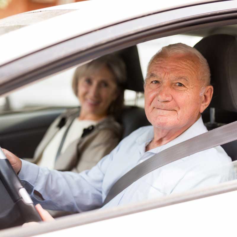 Pareja jubilada en auto disfrutando del camino.