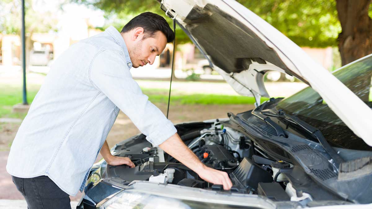Hombre revisando su auto antes de salir a carretera.