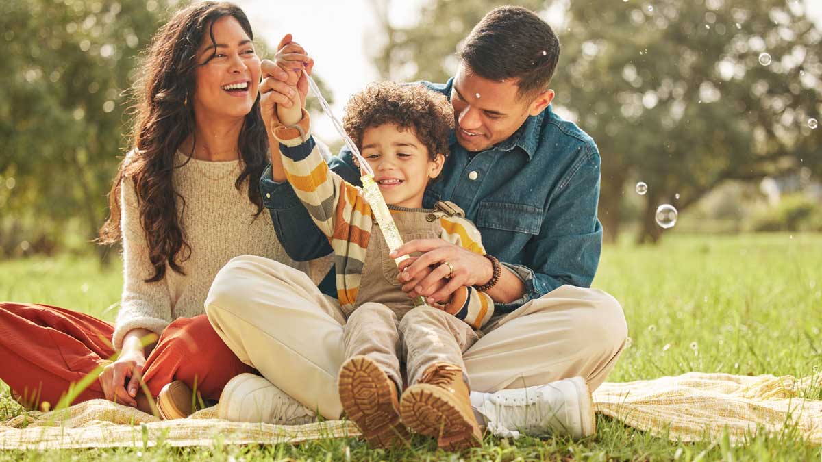 Familia jugando y soplando burbujas, disfrutando en el jardín verde.