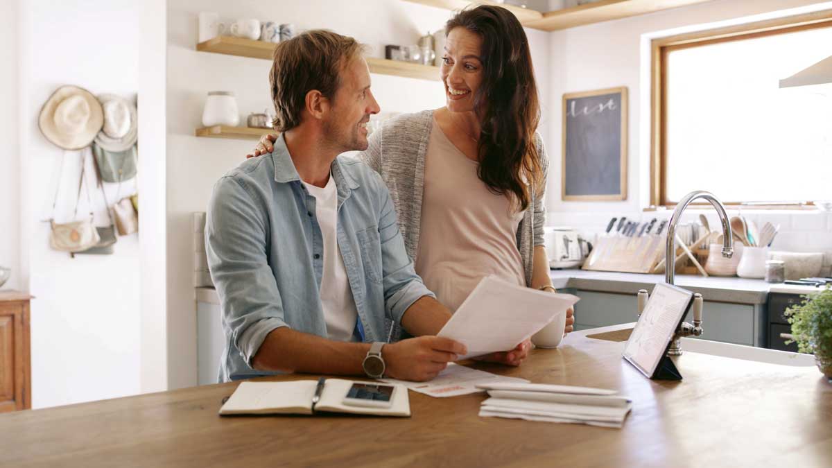 Pareja calculando presupuesto familiar con facturas en la mesa.