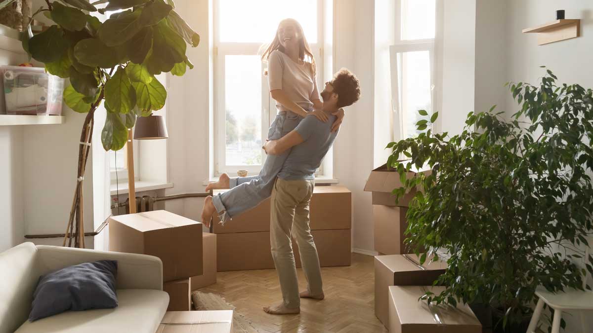 Pareja feliz celebrando mudanza en su nuevo hogar rodeados de cajas.
