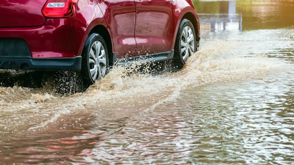 Auto pasando zona de calle inundada.