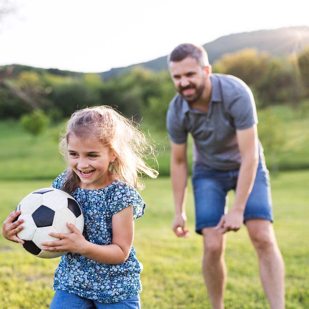 Padre de familia jugando fútbol con su hija menor