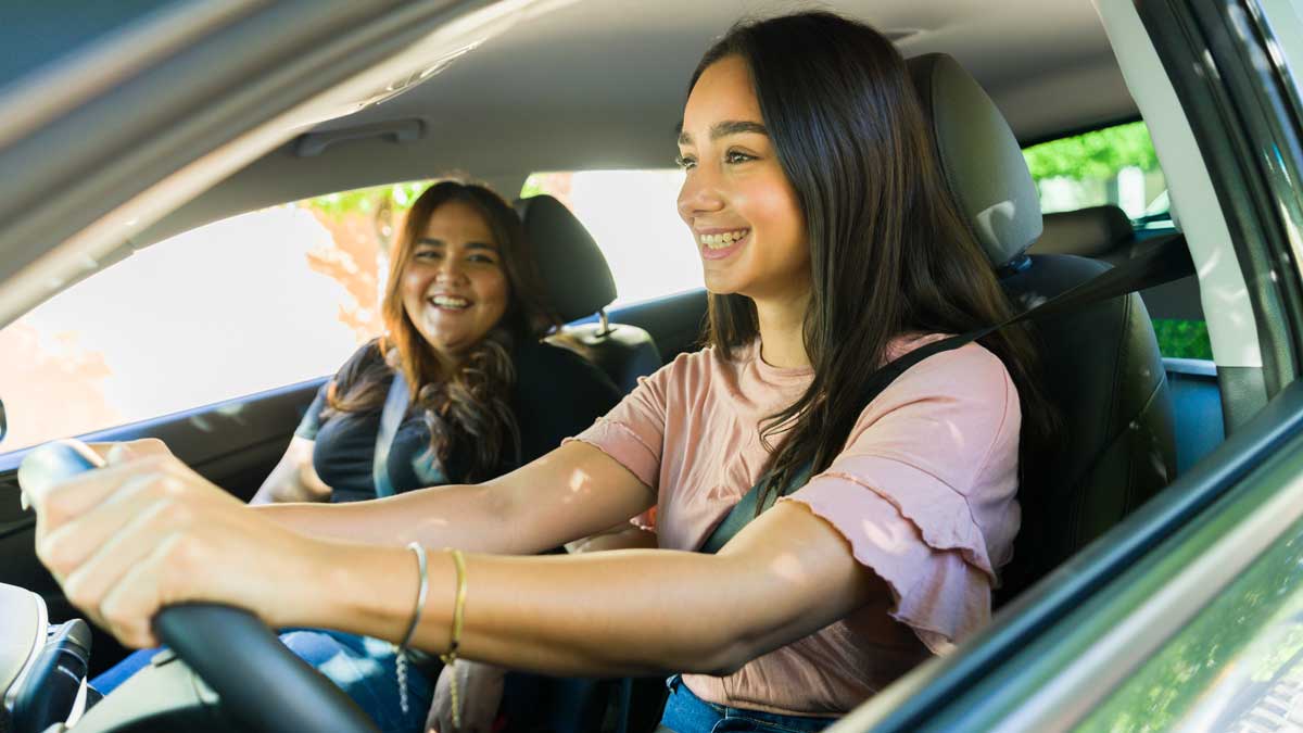 Mamá feliz enseñando a conducir a su hija.