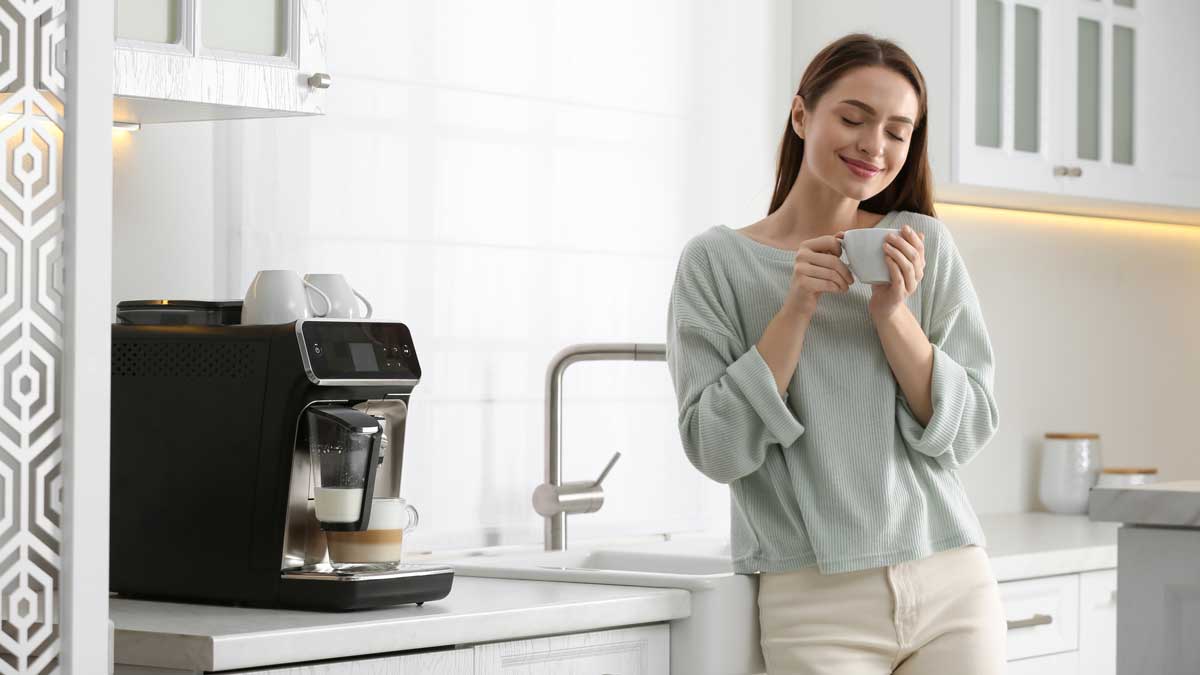 Joven mujer disfrutando un café por la mañana en la cocina de su casa.