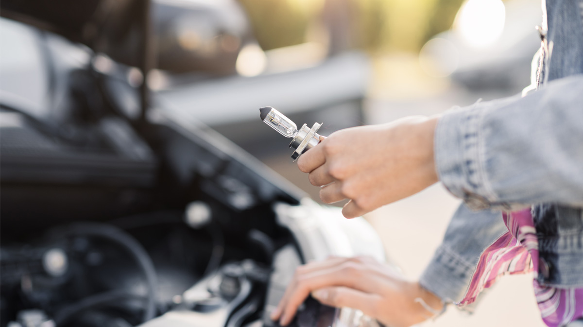 Mujer reemplazando una luz rota de su auto”