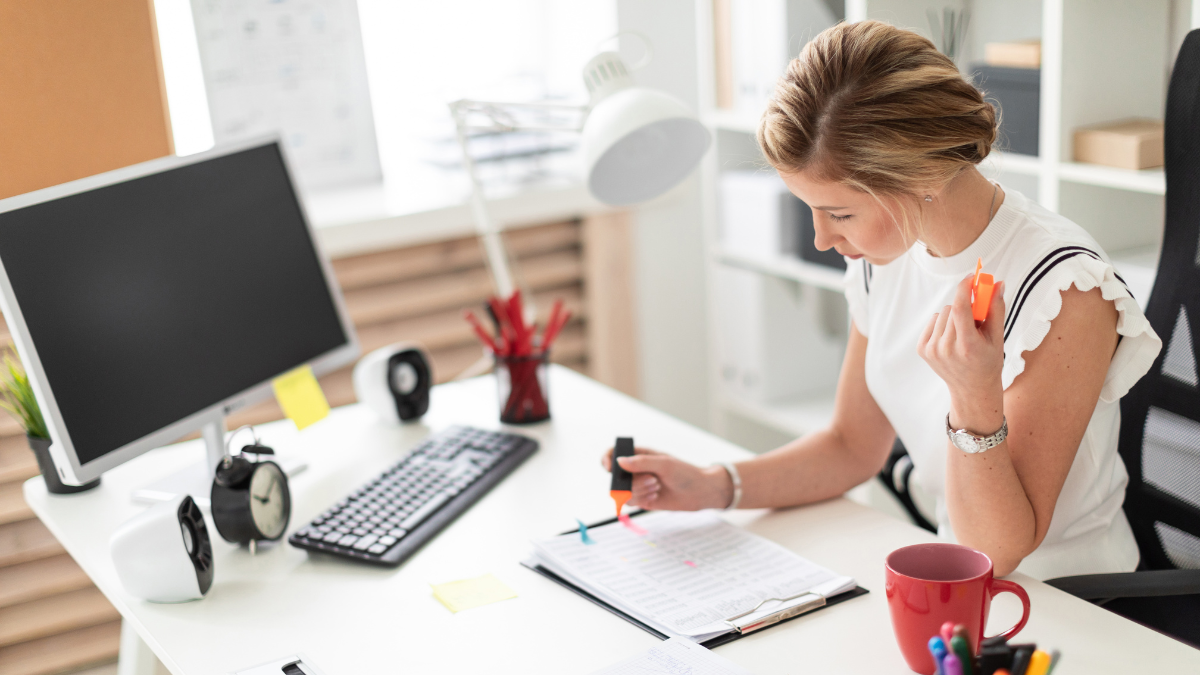 Mujer joven sentada en su escritorio en casa, trabajando con calma y feliz.