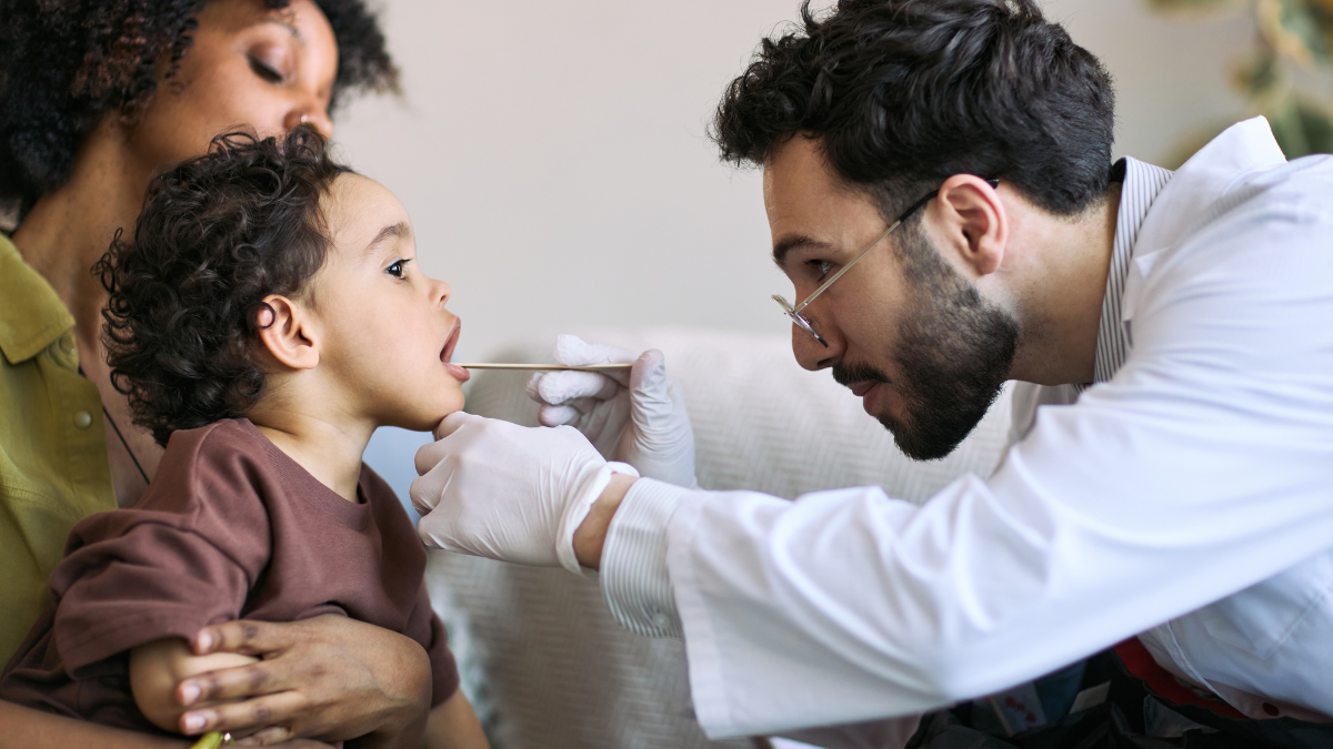 Madre latina sostiene a su hijo durante un examen médico para recibir atención pediátrica