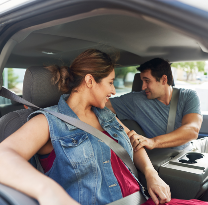 Papá y mamá dentro de auto con el cinturón de seguridad colocado. Hombre y mujer en automóvil a punto de salir de viaje colocándose cinturón de seguridad.