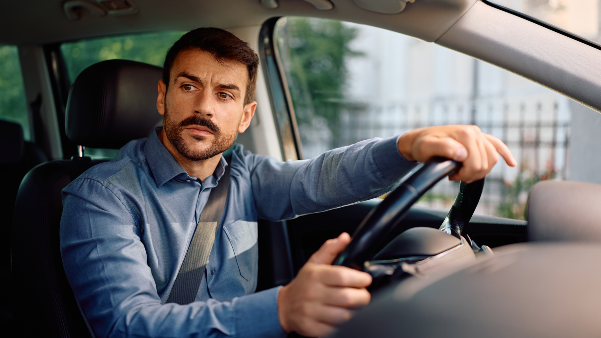 Hombre conduciendo un automóvil mientras observa hacia un costado