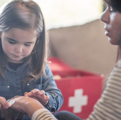 Niña aprendiendo primeros auxilios con ayuda de una persona adulta
