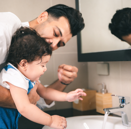 Padre e hijo juntos lavándose las manos para una buena higiene. Padre enseña a su hijo pequeño a lavarse las manos con una sonrisa.