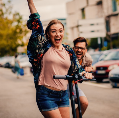 Mujer joven y su amigo disfruta un paseo en scooter eléctrico