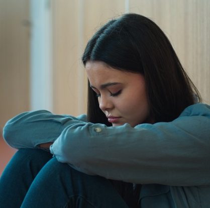 Joven triste, sentada con la cabeza apoyada sobre sus brazos